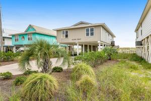 a house with a palm tree in front of it at Sand Trap by Meyer Vacation Rentals in Gulf Shores