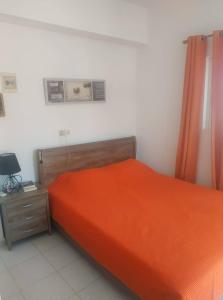 LivadiaにあるSpiros Apartmentsのベッドルーム(オレンジ色のベッド1台、ナイトスタンド付)