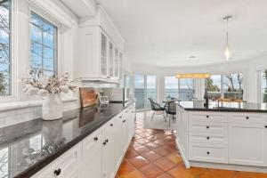 a kitchen with white cabinets and a dining room with a table at Waterfront Cottage on Georgian Bay w Hot Tub in Meaford