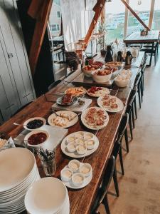 una larga mesa de madera con platos de comida. en Lofoten Links Lodges, en Gimsøy