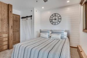 1 dormitorio con 1 cama con reloj en la pared en Laurelwood Condominiums 102, en Snowmass Village