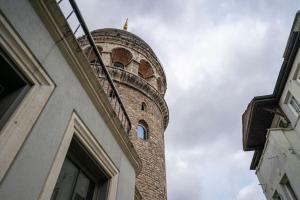 Historic 2 Bedroom Galata Apt-Heart of Istanbul - Kuledibi 1 في إسطنبول: مبنى من الطوب الطويل مع برج الساعة