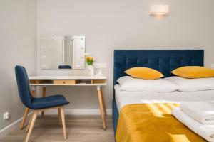 a bed with a blue headboard next to a desk at Apartament na Wspólnej in Elblag