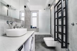 a white bathroom with a sink and a toilet at Apartament na Wspólnej in Elblag