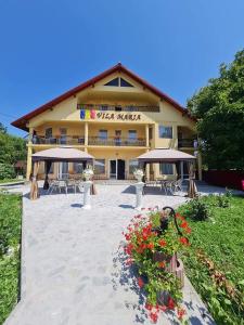 a hotel with tables and umbrellas in front of it at Pensiunea Vila Maria in Crăcăoani