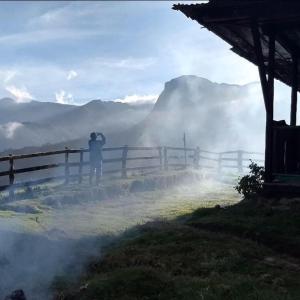 una persona tomando una foto de una valla en las montañas en BIRDGLAMPING LOS ÁRBOLES-Estación Biológica LA GUAYANA, en Salento