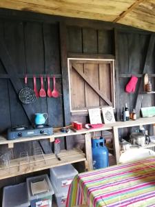 una cocina con estanterías de madera y utensilios en la pared en BIRDGLAMPING LOS ÁRBOLES-Estación Biológica LA GUAYANA, en Salento