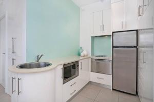 a white kitchen with a sink and a refrigerator at BADEN - Absolute Water Front Sydney Harbour Studio in Sydney
