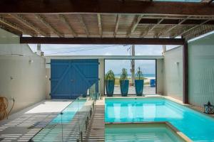 uma piscina com portas azuis e vasos de plantas em Casa do Beiral Azul 5 Qts Pé na areia Piscina em Cabo Frio