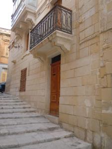 un edificio con balcone e scale di fronte ad una porta di D-House a Birgu (Vittoriosa)