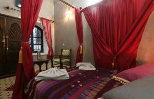 una camera da letto con tende rosse e un letto con sopra dei vestiti di Riad El Bellar a Marrakech