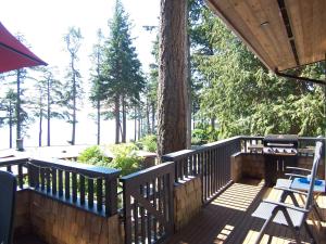 una terraza de madera con un árbol, una mesa y sillas en Malaspina Strait Cottage en Powell River