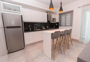 a kitchen with a refrigerator and a counter with stools at Soha Suites II in Santiago de los Caballeros