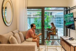 un hombre y una mujer sentados en un sofá en una sala de estar en Singular Dream Beach Residences en Playa del Carmen