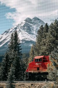 a red train traveling down tracks in front of a mountain at Mountaineer Lodge in Lake Louise
