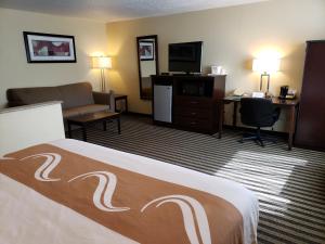 a hotel room with a bed and a desk and a television at Quality Inn & Suites in Vancouver