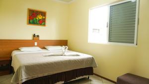 a bedroom with a bed with a white towel on it at HANNA San Diego Apart Hotel in Florianópolis