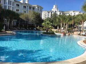 a large blue swimming pool with palm trees and buildings at 3 bedroom Sandestin condo in Baytowne Wharf! in Destin