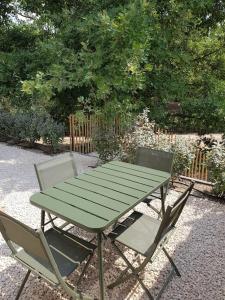 uma mesa de piquenique verde e duas cadeiras num jardim em Le petit écureuil em Saint-Saturnin-dʼApt