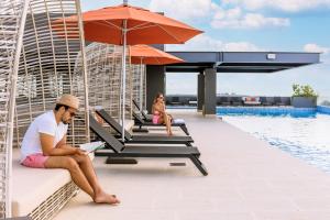 un hombre sentado en un banco junto a una piscina en Singular Dream Beach Residences, en Playa del Carmen