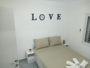 1 dormitorio con 1 cama con la palabra amor en la pared en רימון יחידות אירוח Vacation units RIMON, en Ashkelon