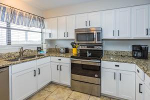 a kitchen with white cabinets and stainless steel appliances at Sunshine At The Beach in Orange Beach