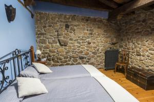 1 dormitorio con 1 cama en una pared de piedra en Casa Altas Crestas, en Puente Pumar