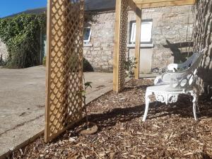 a white bench sitting in front of a fence at Bluebell Cottage in Armagh