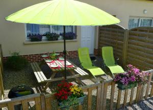 un patio avec une table, des chaises et un parasol dans l'établissement Gîte Les Vents du Large L'Aigrette, au Crotoy