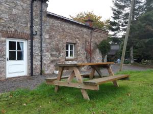 a wooden picnic table in front of a brick building at Bluebell Cottage in Armagh