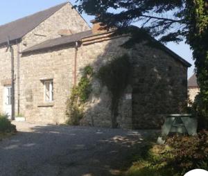 ein Steingebäude mit einer Bank davor in der Unterkunft Bluebell Cottage in Armagh