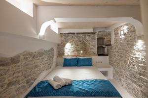 a bedroom with a bed with a stone wall at Margaret's Houses in TINOS Town in Tinos Town
