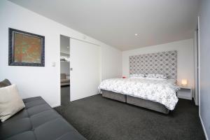 a white bedroom with a bed and a couch at Kohi Beach Bed & Breakfast in Auckland