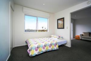 a bedroom with a bed and a window at Kohi Beach Bed & Breakfast in Auckland