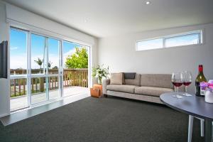 a living room with a couch and a table with wine glasses at Kohi Beach Bed & Breakfast in Auckland