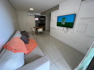 un salon avec un canapé et une télévision à écran plat dans l'établissement Beverly Hills terreo Raul Macedo Neg Imob, à Aquiraz