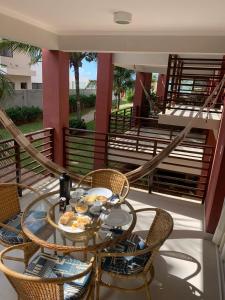 a balcony with a glass table and chairs and stairs at Areias de Itacimirim 104 Village - Pé na Areia in Itacimirim