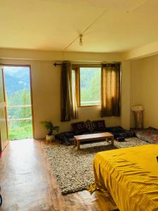 una camera con letto, divano e finestre di The Ivy House Sethan a Manāli