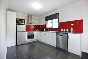 una cocina con electrodomésticos blancos y baldosas rojas en Scarlet Woods, en Quinninup