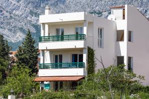 a white building with a mountain in the background at Apartments by the sea Promajna, Makarska - 2642 in Promajna