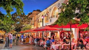 a group of people sitting at tables in a street with umbrellas at Coral Gable 3BR house Parking & in Miami