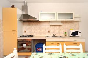 a kitchen with white cabinets and a table and chairs at Apartments by the sea Promajna, Makarska - 2674 in Promajna +14 photos