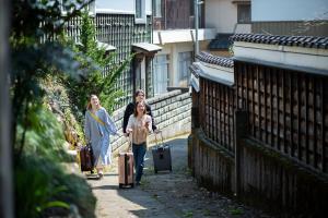 鯖江市にあるSABAE MEGANE HOUSE- Vacation STAY 5077の三人の荷物を持って通りを歩く