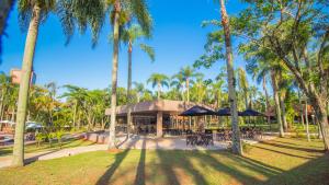 a restaurant with tables and umbrellas in a park with palm trees at Complejo Americano in Puerto Iguazú