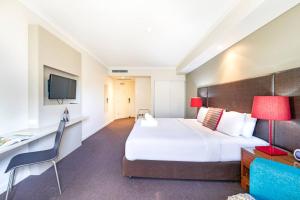 a hotel room with a large bed and a desk at Elevated Waterfront Living on the Esplanades Edge in Darwin
