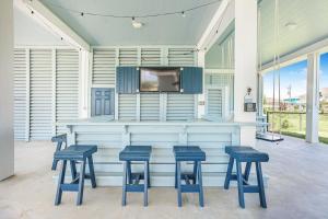 a bar with three blue stools and a tv at Ohana home in Crystal Beach