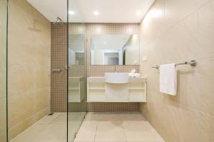 un bagno con doccia in vetro e lavandino di High-Rise Modern Oasis with Pool and City Views a Darwin