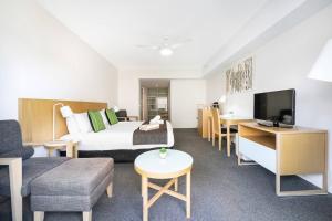 a hotel room with a bed and a couch and a tv at King Balcony Suite at Resort Style Darwin Stay in Darwin