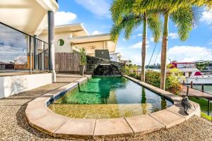 a swimming pool in the backyard of a house with palm trees at Luxe Bayview Oasis with Dream Waterfront Pool in Stuart Park