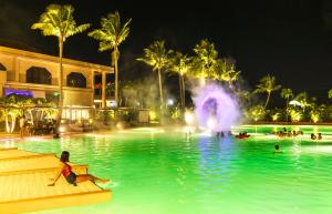 einen Pool in einem Resort in der Nacht mit einem Brunnen in der Unterkunft Coral Ocean Resort in Saipan